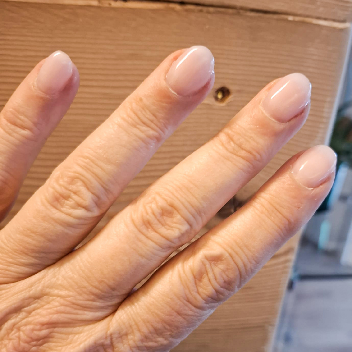 Manicure femminile con applicazione di smalto semipermanente molto naturale color rosa in centro estetico