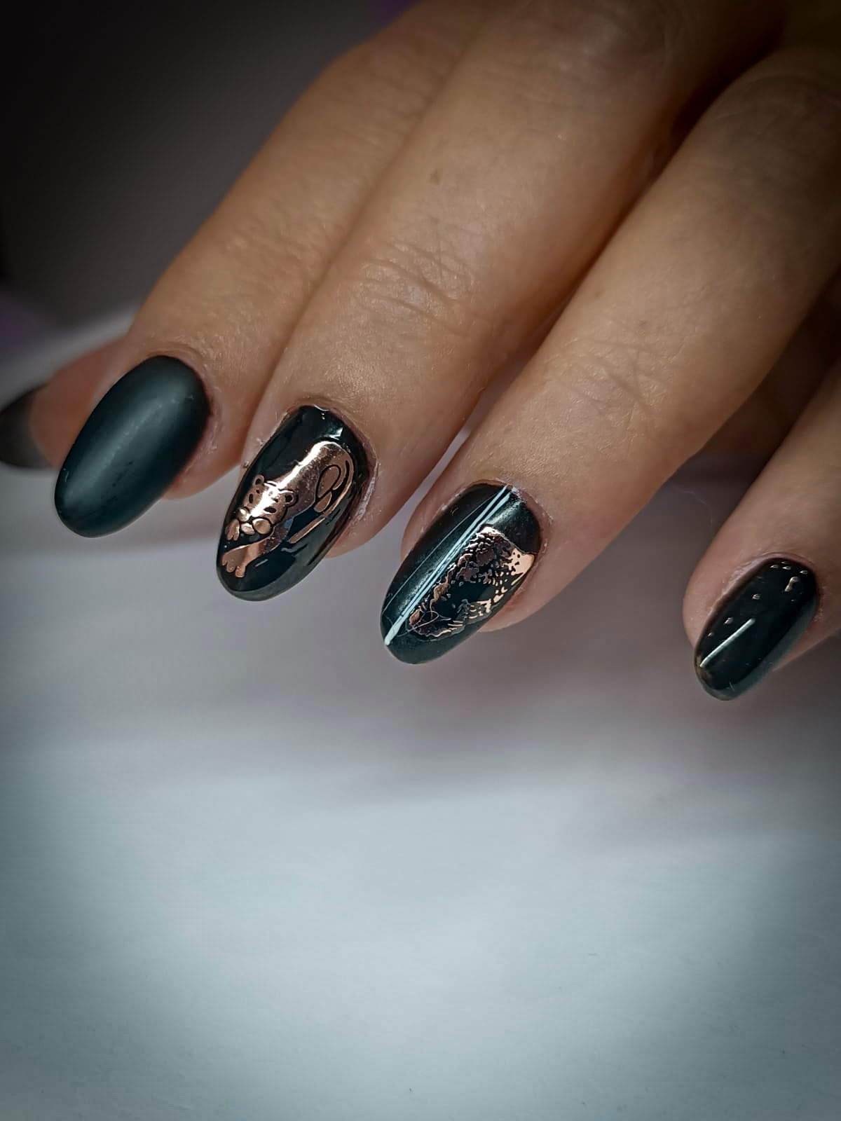 Manicure con smalto gel nero e nail art in oro rosa, decorazioni raffinate su unghie dalla forma ovale e finish lucido-opaco