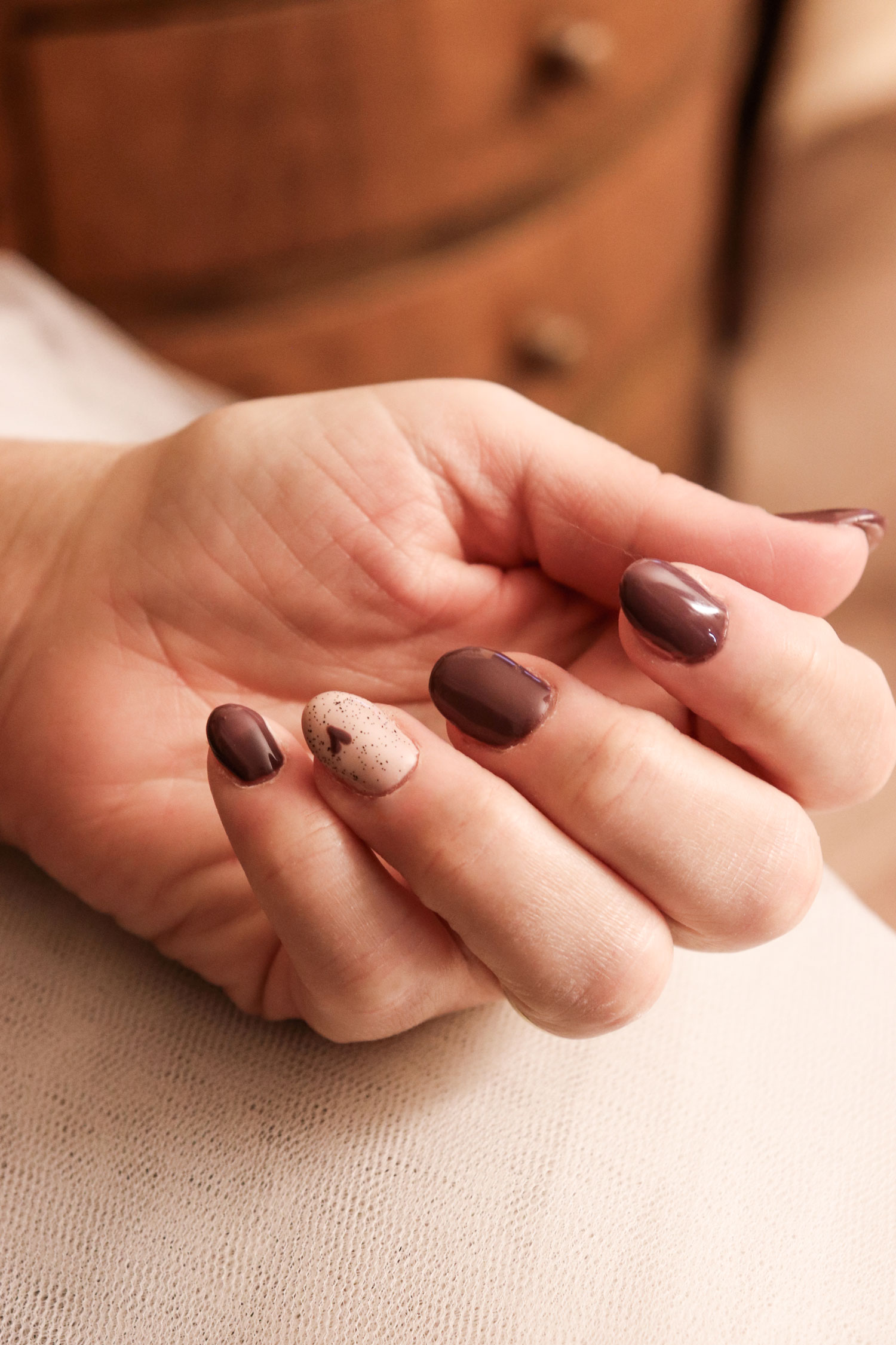 Unghie curate con manicure in semipermanente dal finish lucido e duraturo. é una manicure sui toni del marrone, l'unico dito differente è l'anulare , l'unghia ha una base beige con un cuoricino marrone, sopra un top brillantinato